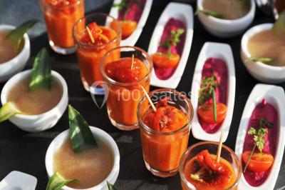 Brasero allumé dans une cour gravillonnée devant un bâtiment éclairé avec des murs en bois et des portes vitrées.