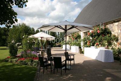 Brasero allumé dans une cour gravillonnée devant un bâtiment éclairé avec des murs en bois et des portes vitrées.