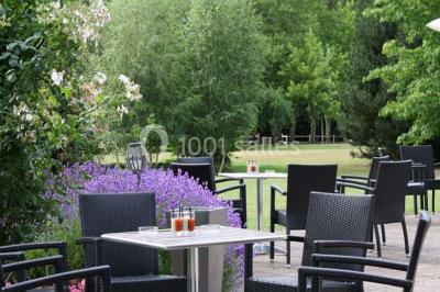 Brasero allumé dans une cour gravillonnée devant un bâtiment éclairé avec des murs en bois et des portes vitrées.