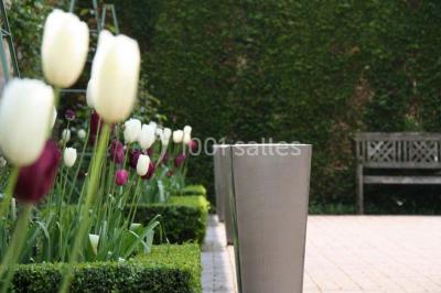 Brasero allumé dans une cour gravillonnée devant un bâtiment éclairé avec des murs en bois et des portes vitrées.