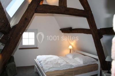 Brasero allumé dans une cour gravillonnée devant un bâtiment éclairé avec des murs en bois et des portes vitrées.