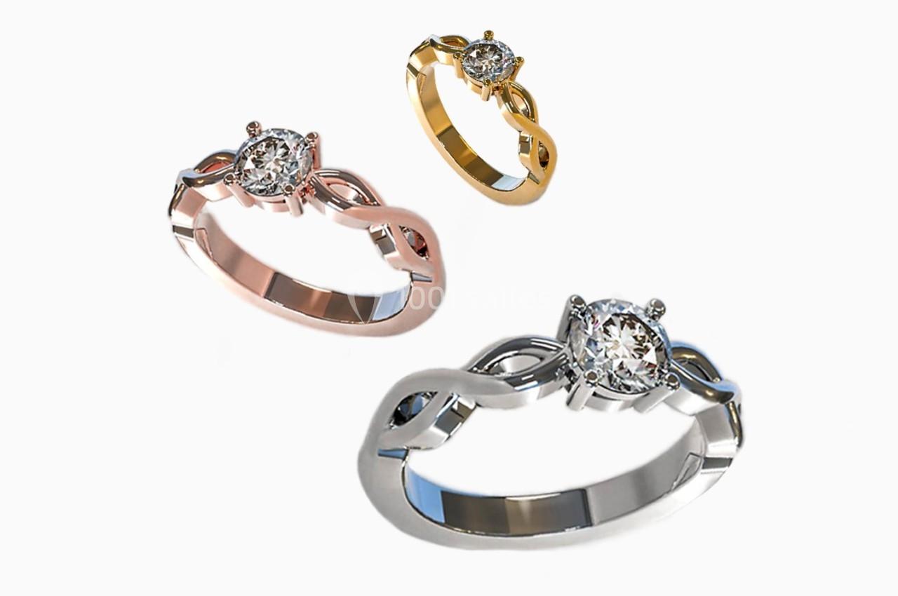 Trois bagues en or blanc, rose et jaune avec un diamant central et un design entrelacé.