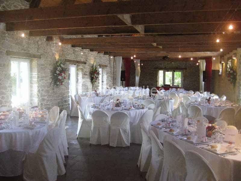 Location salle Douarnenez (Finistère) - La Ferme de Trézulien #8 Salle de réception en pierre avec tables rondes dressées, nappes blanches et décorations florales.