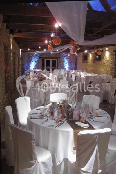 Location salle Douarnenez (Finistère) - La Ferme de Trézulien #9 Salle de réception décorée avec des tables rondes, nappes blanches, chaises houssées et éclairage tamisé.