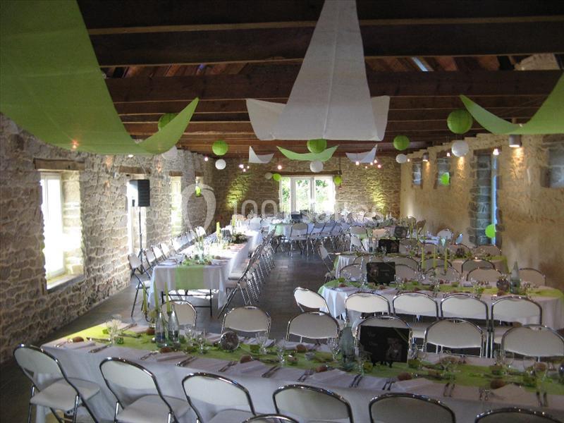 Location salle Douarnenez (Finistère) - La Ferme de Trézulien #17 Salle décorée pour un événement, avec tables dressées, chaises blanches et guirlandes vertes suspendues au plafond.