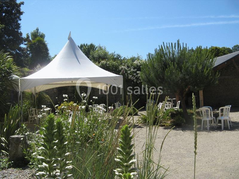 Location salle Douarnenez (Finistère) - La Ferme de Trézulien #21 Tente blanche installée dans un jardin avec des chaises blanches disposées sur un sol gravillonné.