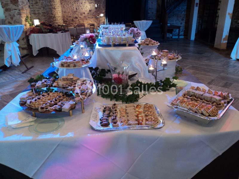 Buffet de réception avec divers plats et desserts disposés sur des plateaux, entourés de bougies et de décorations florales.