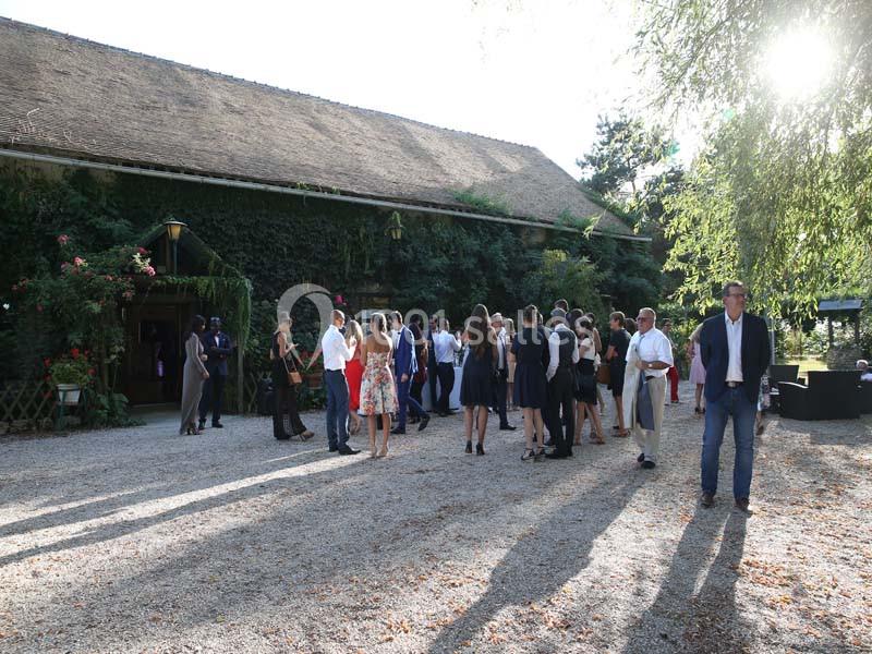 Groupe de personnes discutant devant un bâtiment couvert de végétation, par une journée ensoleillée.