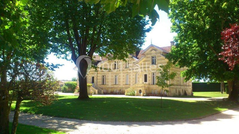 Location salle Moulis-en-Médoc (Gironde) - Château Maucaillou #3 Manoir en pierre entouré d'arbres et de pelouses, avec un chemin gravillonné au premier plan.