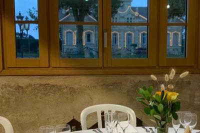 Miniature Location salle Moulis-en-Médoc (Gironde) - Château Maucaillou #21 Salle à manger élégante avec table dressée, bouquet de fleurs au centre, grande fenêtre ouverte sur un jardin verdoyant.