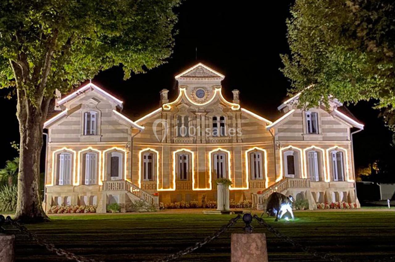 Location salle Moulis-en-Médoc (Gironde) - Château Maucaillou #9 Façade d'un bâtiment illuminé la nuit, entouré d'arbres et d'une pelouse bien entretenue.