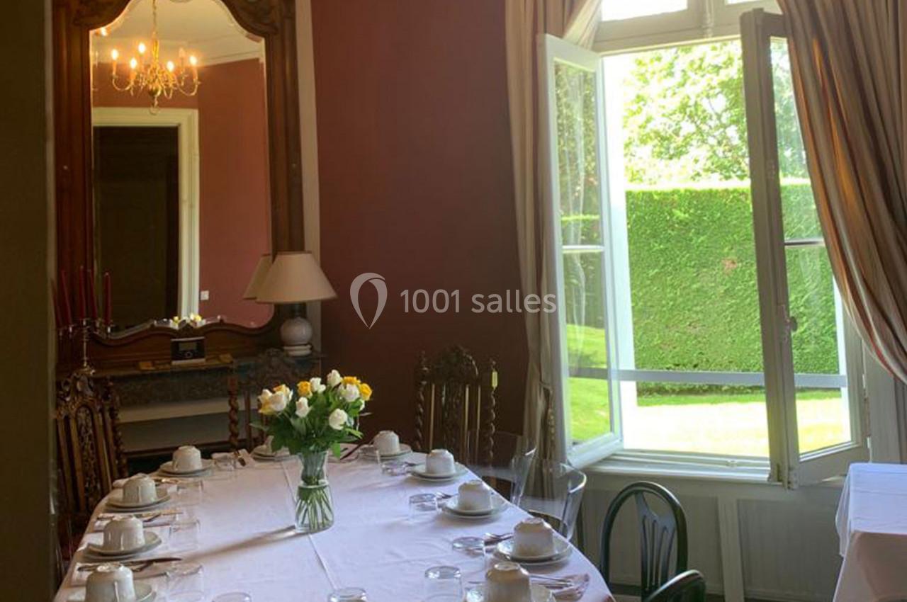 Location salle Moulis-en-Médoc (Gironde) - Château Maucaillou #27 Salle à manger élégante avec table dressée, bouquet de fleurs au centre, grande fenêtre ouverte sur un jardin verdoyant.