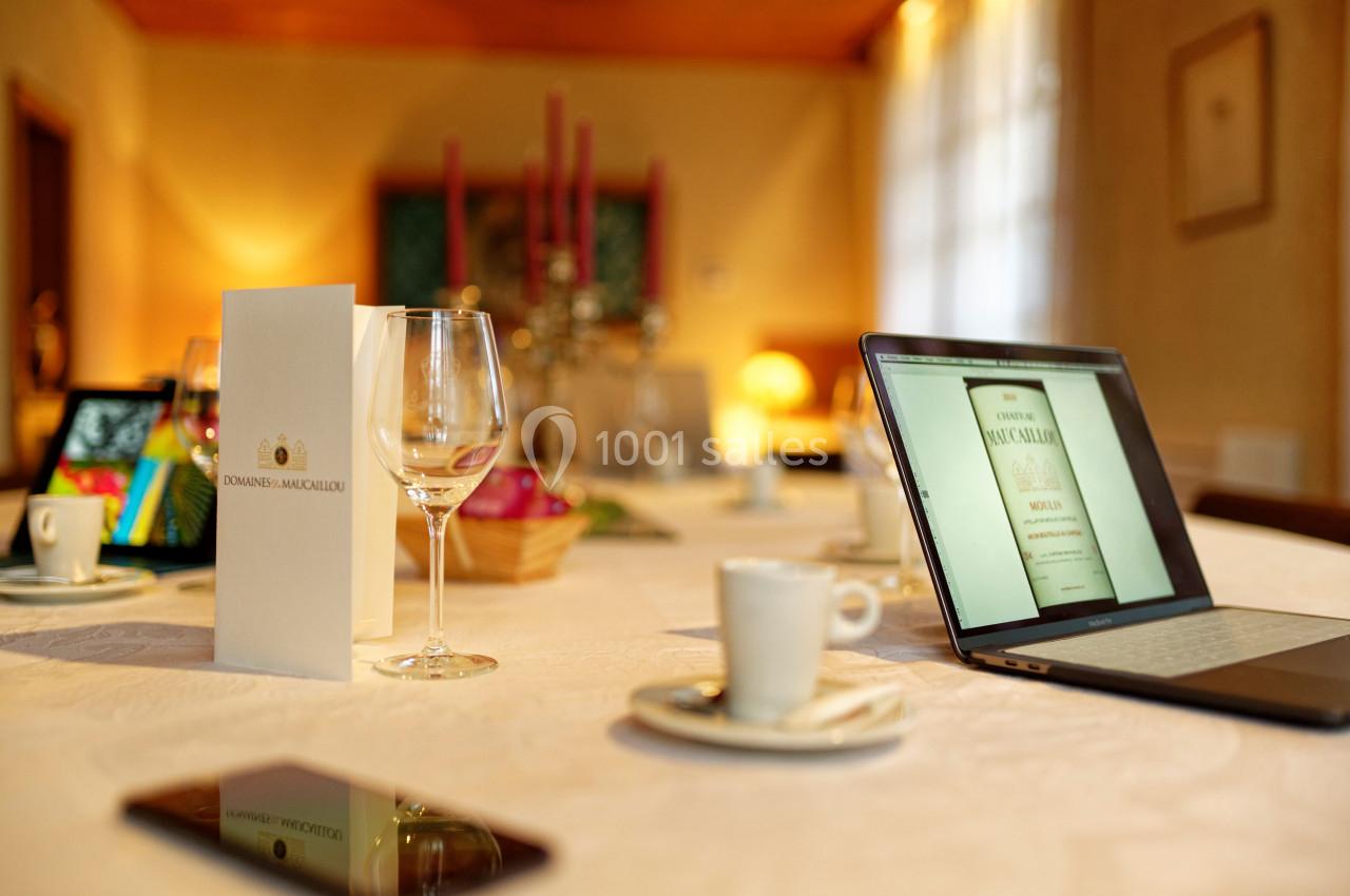 Location salle Moulis-en-Médoc (Gironde) - Château Maucaillou #2 Table dressée avec des verres, tasses à café, un ordinateur portable affichant une page, et un menu debout.