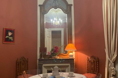 Château entouré d'arbres, table élégamment dressée, bouteille de champagne et espace de travail avec ordinateur.