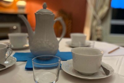 Château entouré d'arbres, table élégamment dressée, bouteille de champagne et espace de travail avec ordinateur.