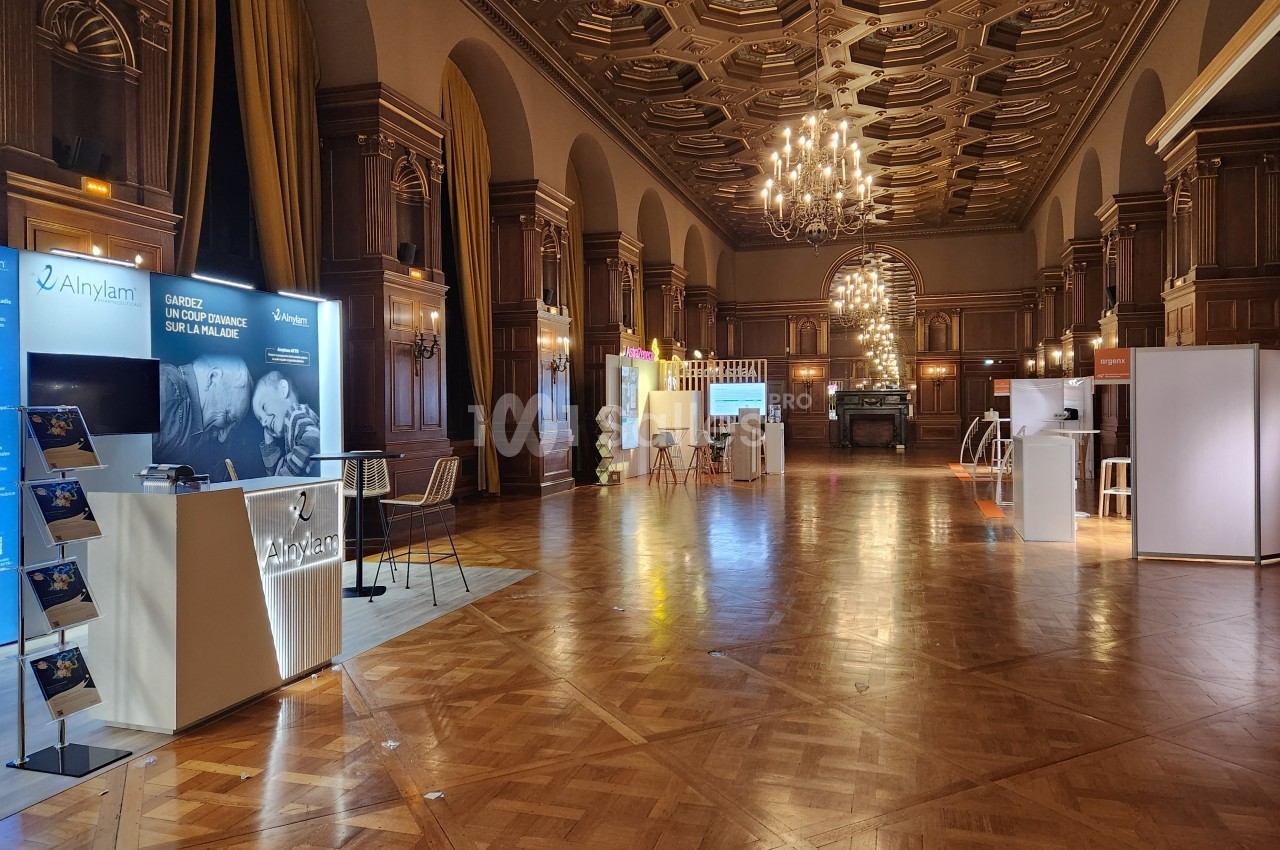 Salle de conférence élégante avec stands d'exposition, parquet en bois et lustres suspendus.