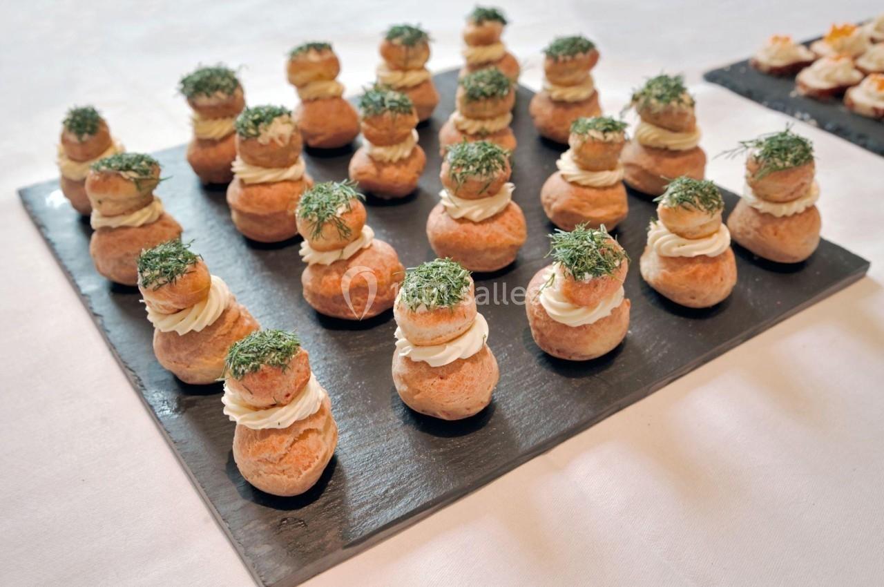 Choux garnis de crème et décorés d'aneth, disposés en rangées sur des ardoises noires.