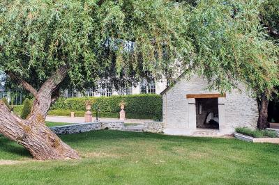 Miniature Location salle Longnes (Yvelines) - Domaine des Clos Vallées #15 Couronne de fleurs blanches et roses suspendue à un arbre sous la lumière du soleil dans un jardin verdoyant.