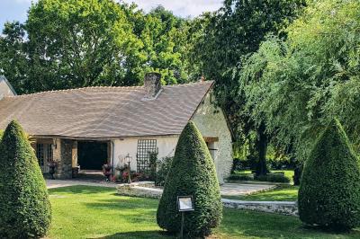 Miniature Location salle Longnes (Yvelines) - Domaine des Clos Vallées #45 Couronne de fleurs blanches et roses suspendue à un arbre sous la lumière du soleil dans un jardin verdoyant.