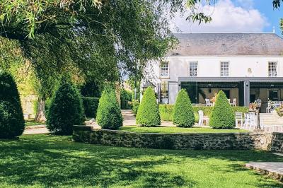 Miniature Location salle Longnes (Yvelines) - Domaine des Clos Vallées #23 Couronne de fleurs blanches et roses suspendue à un arbre sous la lumière du soleil dans un jardin verdoyant.