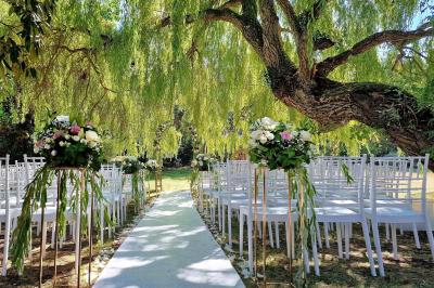 Miniature Location salle Longnes (Yvelines) - Domaine des Clos Vallées #3 Couronne de fleurs blanches et roses suspendue à un arbre sous la lumière du soleil dans un jardin verdoyant.