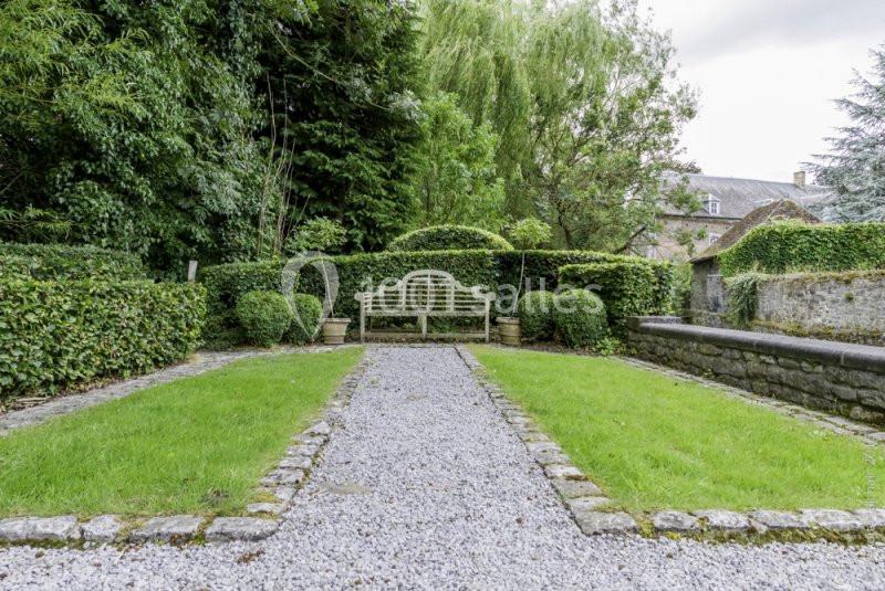 Location salle Anhée (Namur) - Ferme de l'Abbaye de Moulins #11 Allée de gravier bordée de pelouses et de haies, menant à un banc en bois blanc dans un jardin verdoyant.