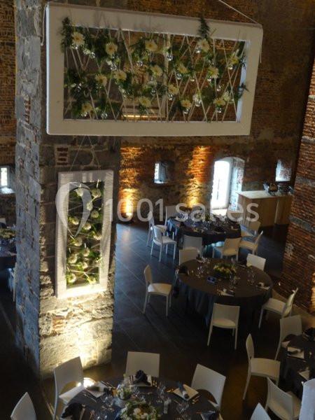 Location salle Anhée (Namur) - Ferme de l'Abbaye de Moulins #14 Salle de réception en briques avec tables dressées et décorations florales suspendues.