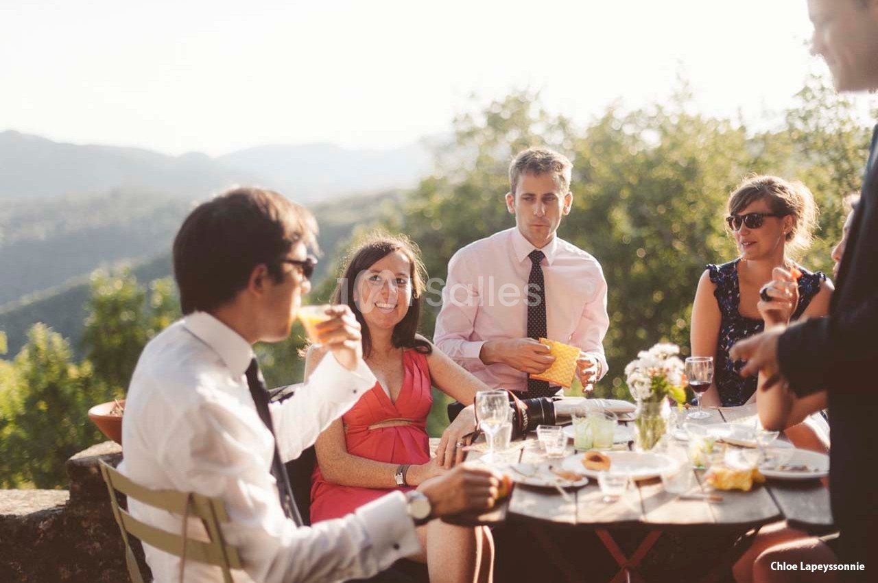 Groupe de personnes partageant un repas en extérieur, autour d'une table, dans un cadre naturel ensoleillé.