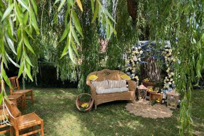 Salle de réception rustique avec poutres en bois apparentes, tables rondes dressées et chaises rouges.