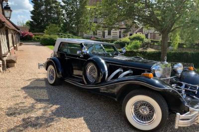Salle de réception rustique avec poutres en bois apparentes, tables rondes dressées et chaises rouges.