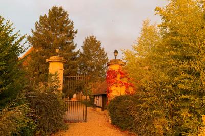 Salle de réception rustique avec poutres en bois apparentes, tables rondes dressées et chaises rouges.