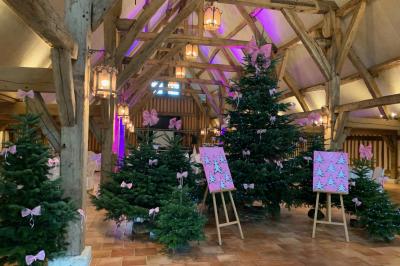 Salle de réception rustique avec poutres en bois apparentes, tables rondes dressées et chaises rouges.