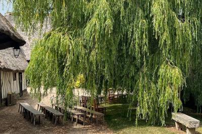 Salle de réception rustique avec poutres en bois apparentes, tables rondes dressées et chaises rouges.