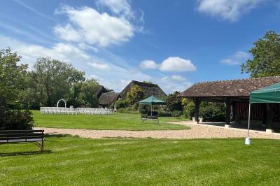 Salle de réception rustique avec poutres en bois apparentes, tables rondes dressées et chaises rouges.