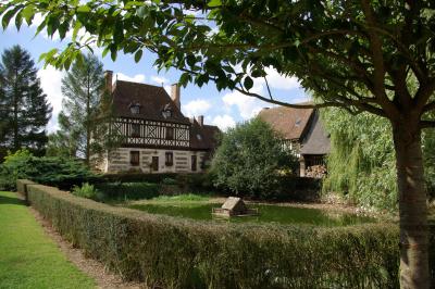 Salle de réception rustique avec poutres en bois apparentes, tables rondes dressées et chaises rouges.
