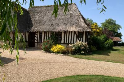 Salle de réception rustique avec poutres en bois apparentes, tables rondes dressées et chaises rouges.