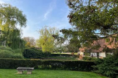 Salle de réception rustique avec poutres en bois apparentes, tables rondes dressées et chaises rouges.