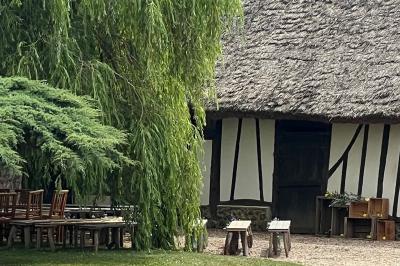 Salle de réception rustique avec poutres en bois apparentes, tables rondes dressées et chaises rouges.