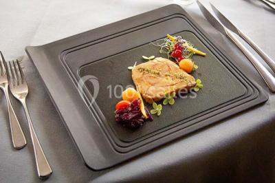 Assiette gastronomique avec une entrée élégamment dressée, comprenant foie gras, garnitures et décorations végétales.
