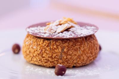 Rouleau croustillant servi sur un lit de légumes colorés avec une garniture florale sur une assiette blanche.
