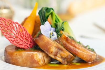 Rouleau croustillant servi sur un lit de légumes colorés avec une garniture florale sur une assiette blanche.