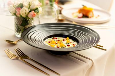 Rouleau croustillant servi sur un lit de légumes colorés avec une garniture florale sur une assiette blanche.