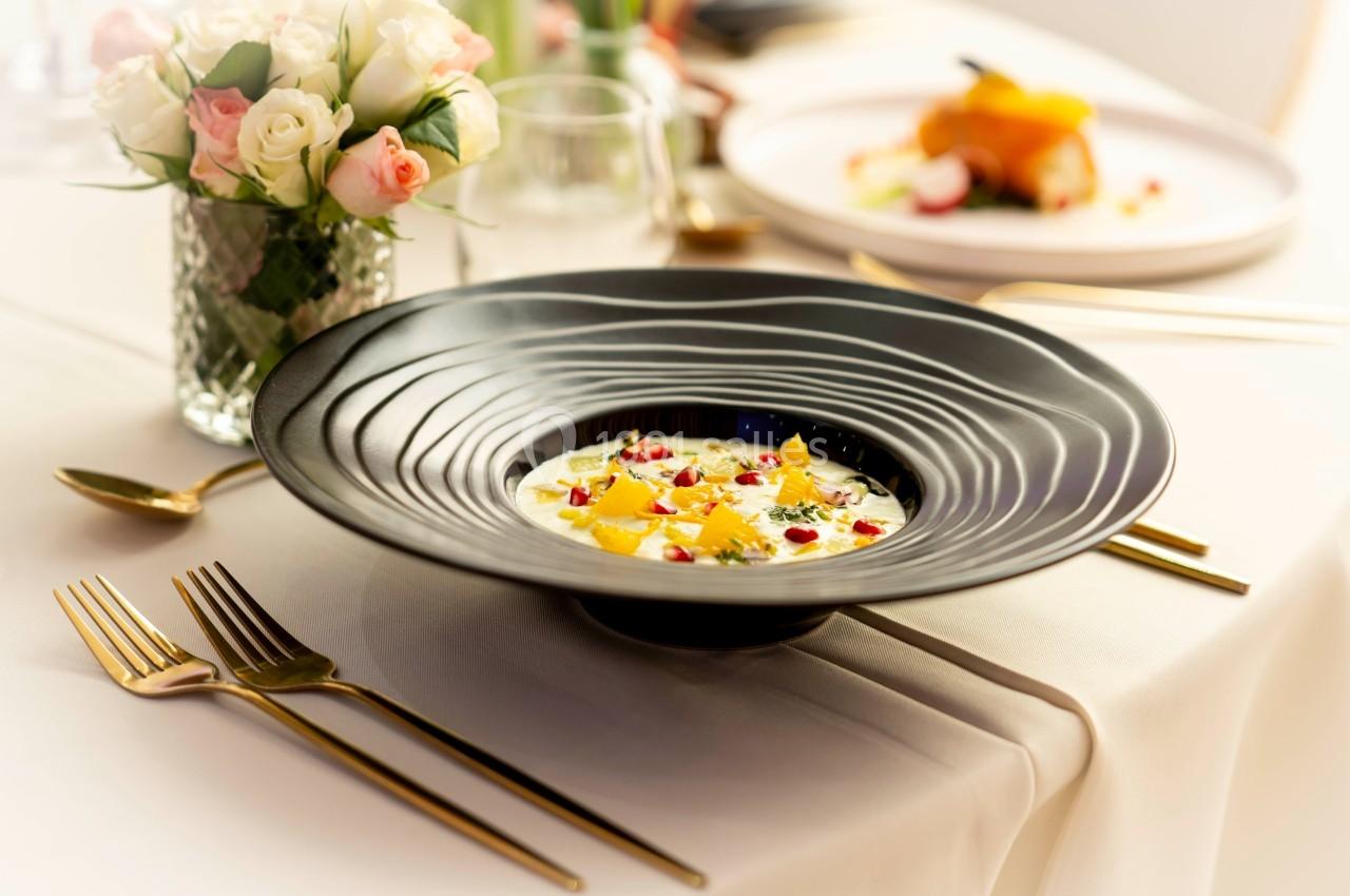 Assiette gastronomique avec une présentation colorée de fruits et herbes, posée sur une table élégamment dressée.