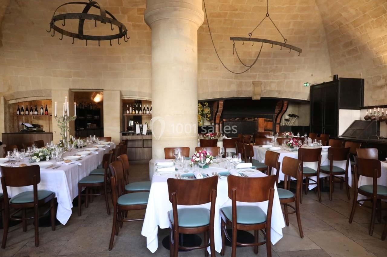 Location salle Chantilly (Oise) - La Capitainerie du Château de Chantilly #11 Salle de restaurant avec tables dressées, nappes blanches, chaises en bois et décor en pierre voûtée.