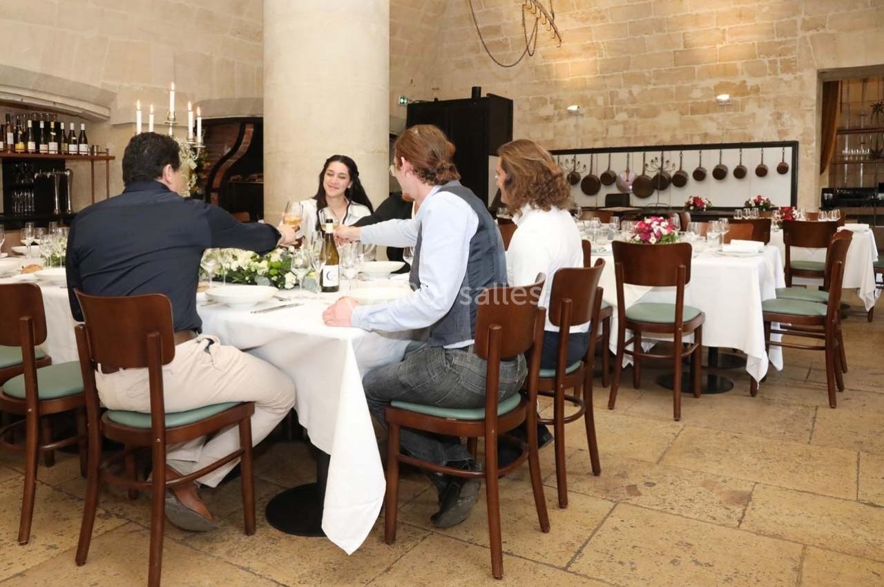 Location salle Chantilly (Oise) - La Capitainerie du Château de Chantilly #15 Des personnes trinquent autour d'une table dans une salle de restaurant élégante avec des murs en pierre.