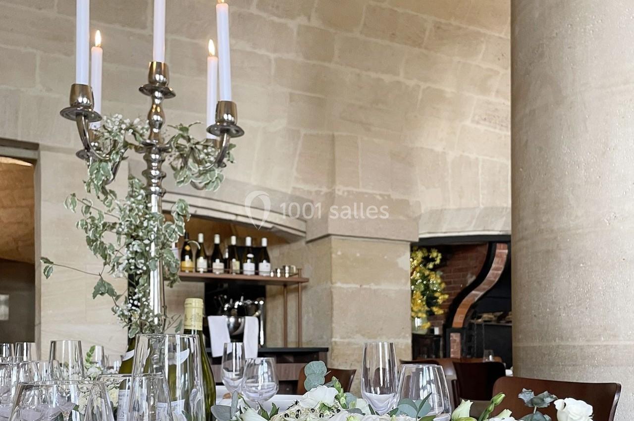 Location salle Chantilly (Oise) - La Capitainerie du Château de Chantilly #16 Table élégamment dressée avec chandeliers, fleurs blanches et verres, dans une salle voûtée en pierre.