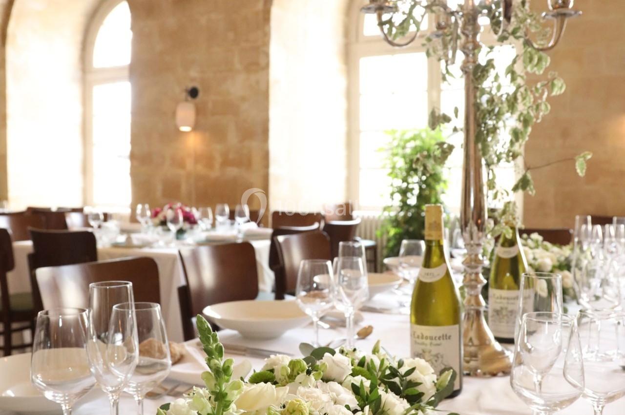 Location salle Chantilly (Oise) - La Capitainerie du Château de Chantilly #19 Salle de réception lumineuse avec tables dressées, décorations florales et bouteilles de vin.