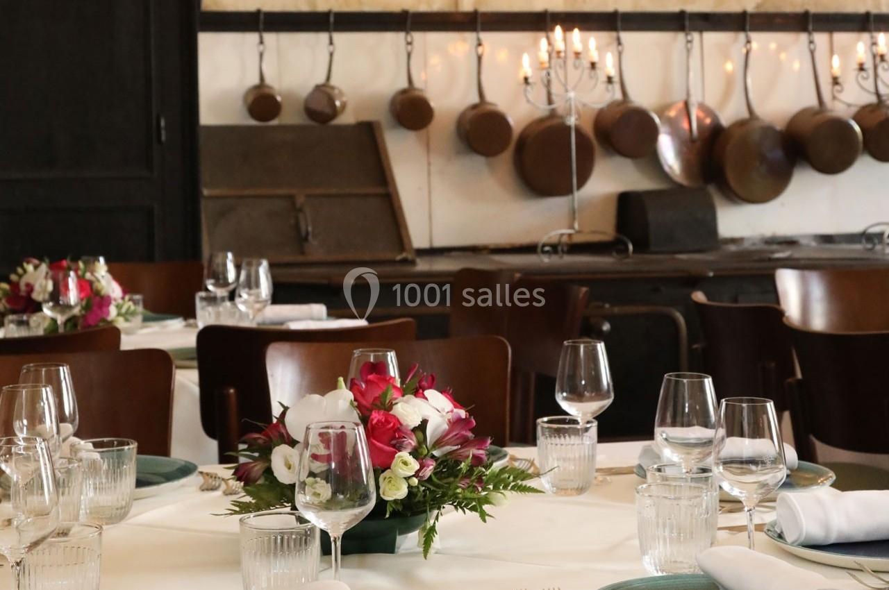 Location salle Chantilly (Oise) - La Capitainerie du Château de Chantilly #28 Salle à manger élégante avec tables dressées, compositions florales et cuisine ancienne en arrière-plan.