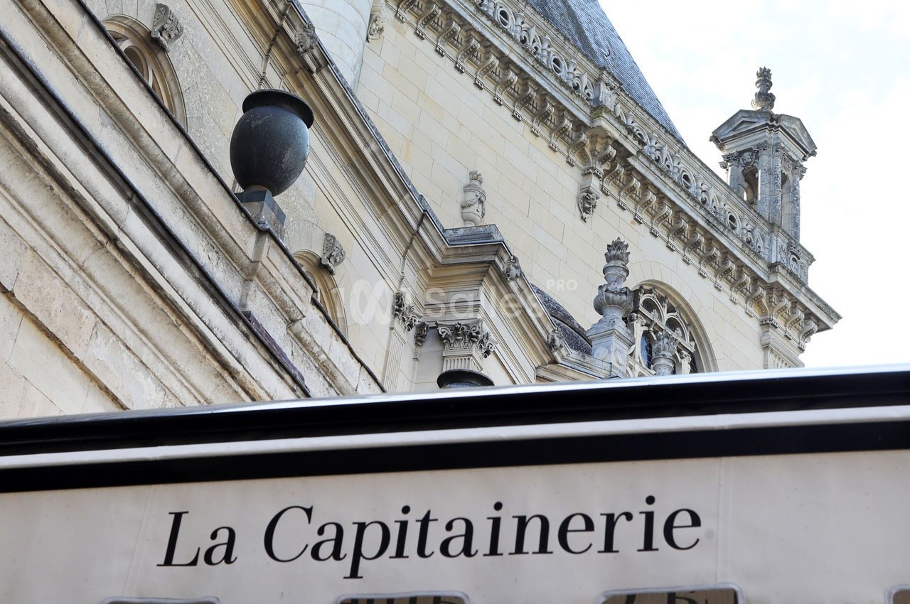 Façade en pierre d'un bâtiment historique avec une enseigne ’La Capitainerie’ au premier plan.