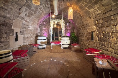 Comptoir lumineux dans une pièce voûtée en pierre, décoré de plantes, lampes et guirlandes lumineuses.